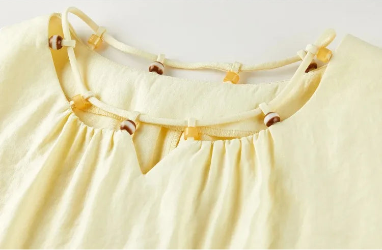 Close-up of the top's neckline with a central notch, decorative drawstring, and handcrafted beaded loops — From Borcelleclothes.