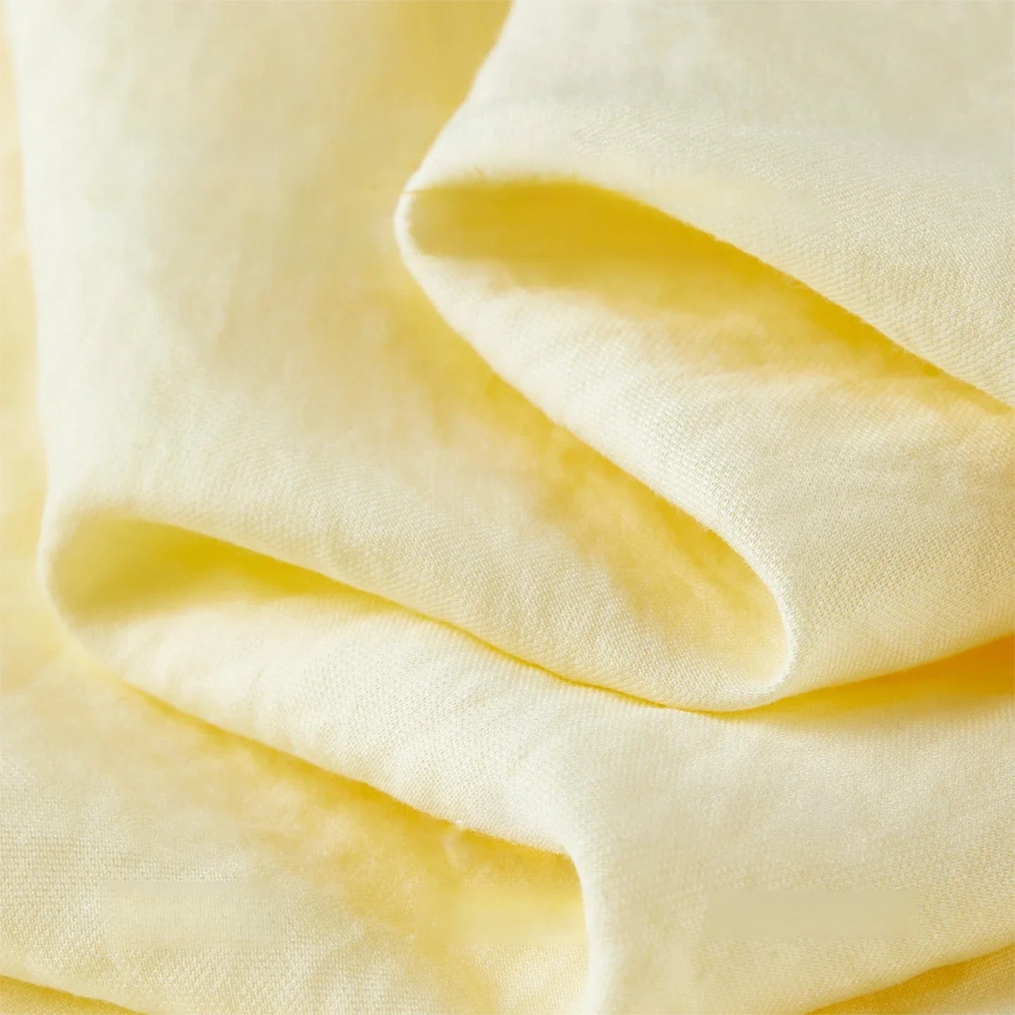Close-up of the wave-folded crinkled texture of the natural viscose fabric in sunny yellow — From Borcelleclothes.