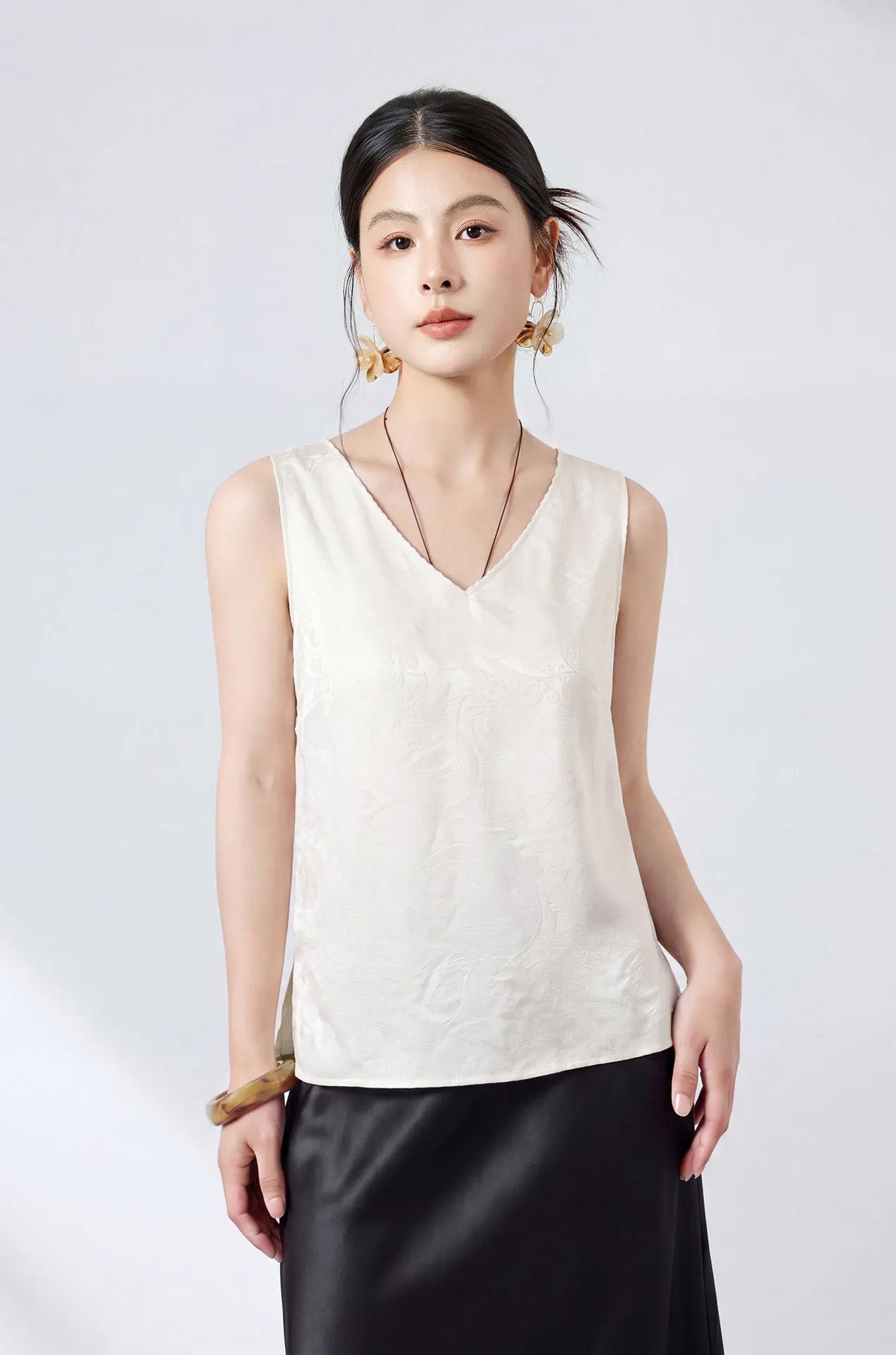 Model with hands on hips wearing an ivory Melting Ice Lace viscose-silk jacquard top with refined picot trim. — From Borcelleclothes.