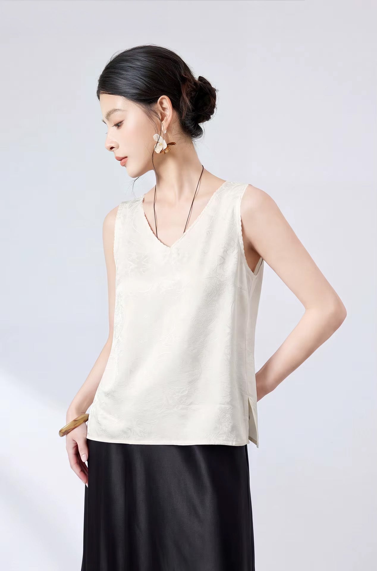 Side profile of a model showcasing the relaxed silhouette of a Melting Ice Lace silk jacquard sleeveless top. — From Borcelleclothes.