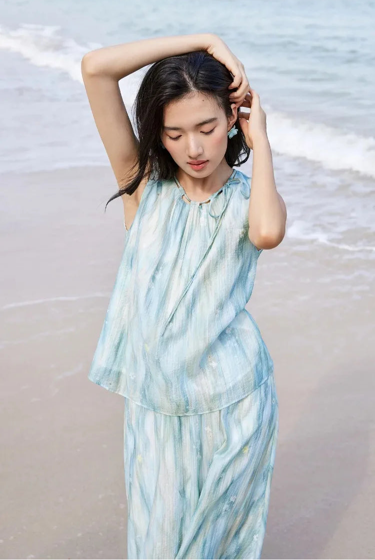 Close-up of a woman in the watercolor top, her hands in her hair, showcasing the delicate neckline — From Borcelleclothes.