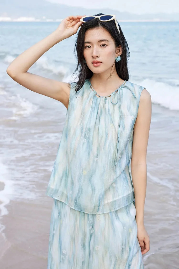 Summer aesthetic of a woman in a breezy watercolor outfit adjusting sunglasses on her head — From Borcelleclothes.
