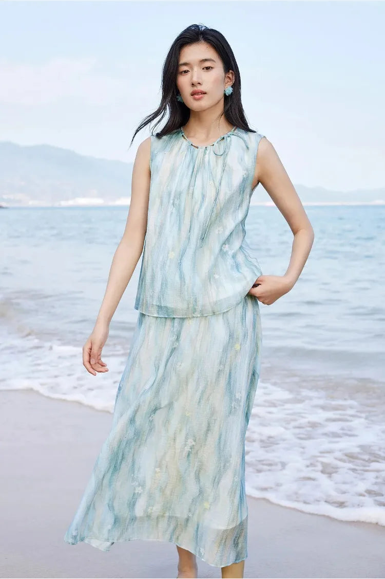 A woman's hand feeling the lightweight and soft texture of the blue watercolor lyocell top — From Borcelleclothes.