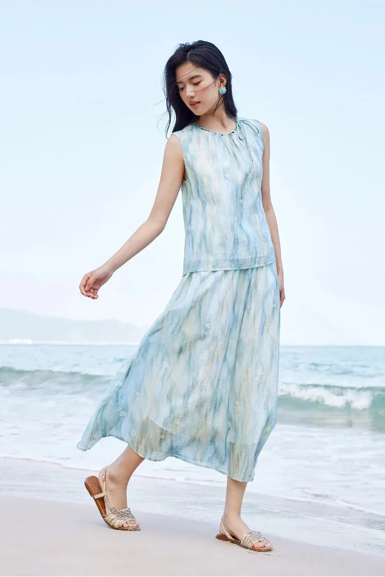 The dramatic flared skirt of the watercolor lyocell set moving beautifully with a woman's step on the sand — From Borcelleclothes.
