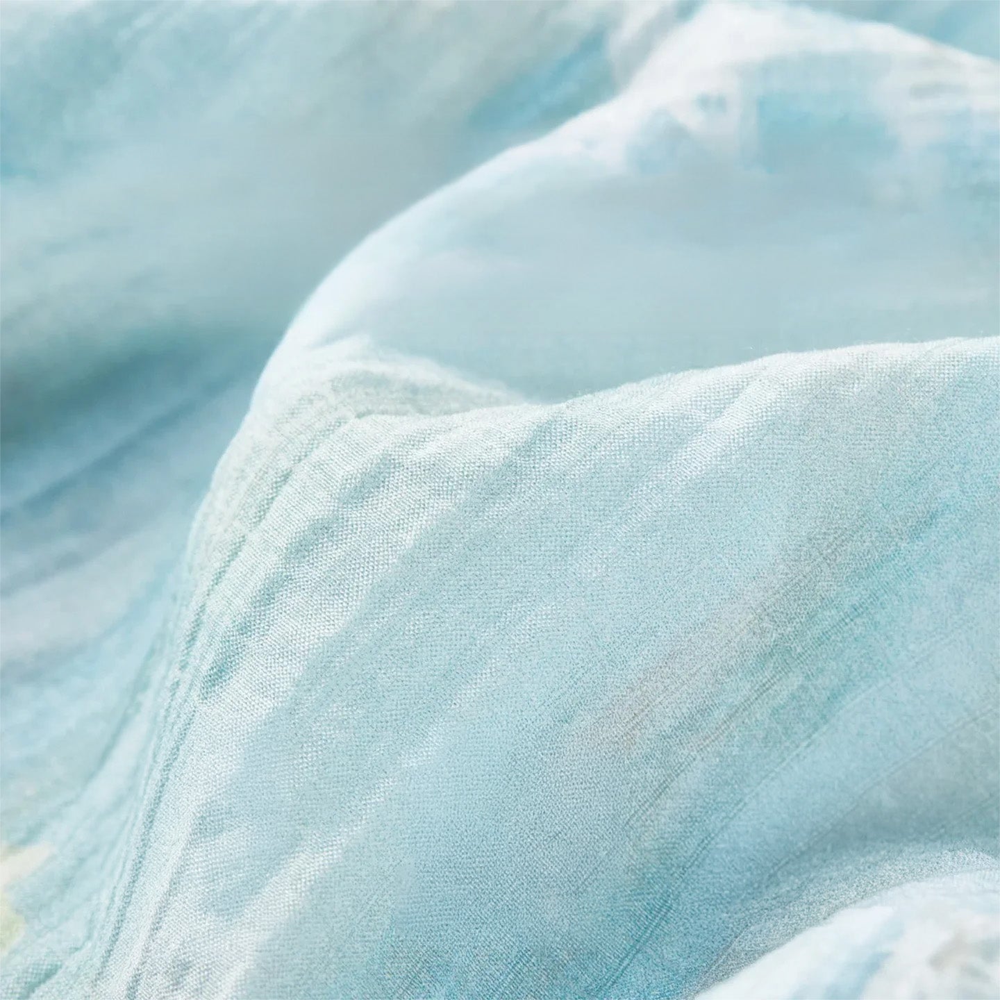 Close-up of the breathable lyocell fabric with a soft crinkled texture and blurred floral print — From Borcelleclothes.