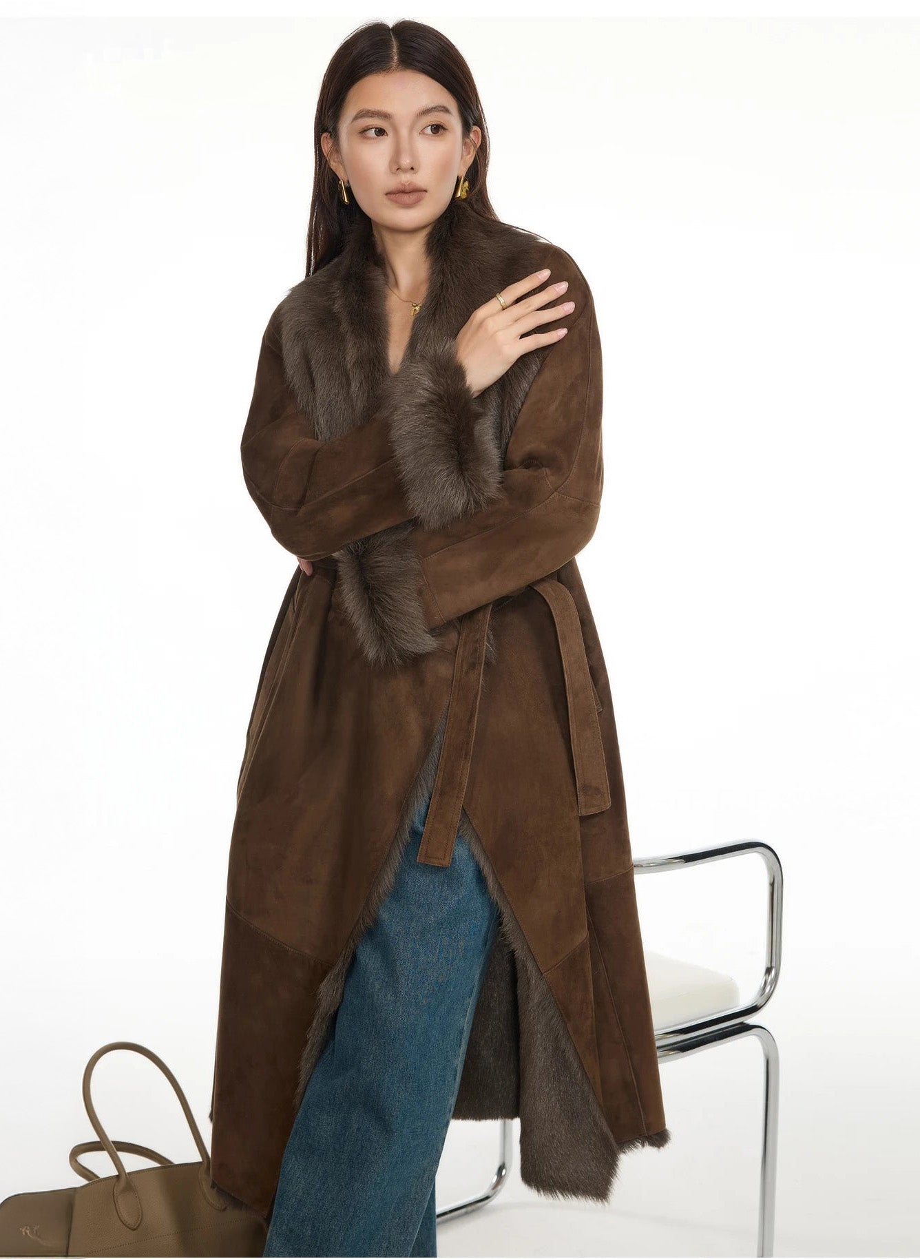 Model resting her hand on shoulder while wearing a double-faced goatskin coat in Woodsy Brown, showcasing the wide lapel design — From Borcelleclothes.
