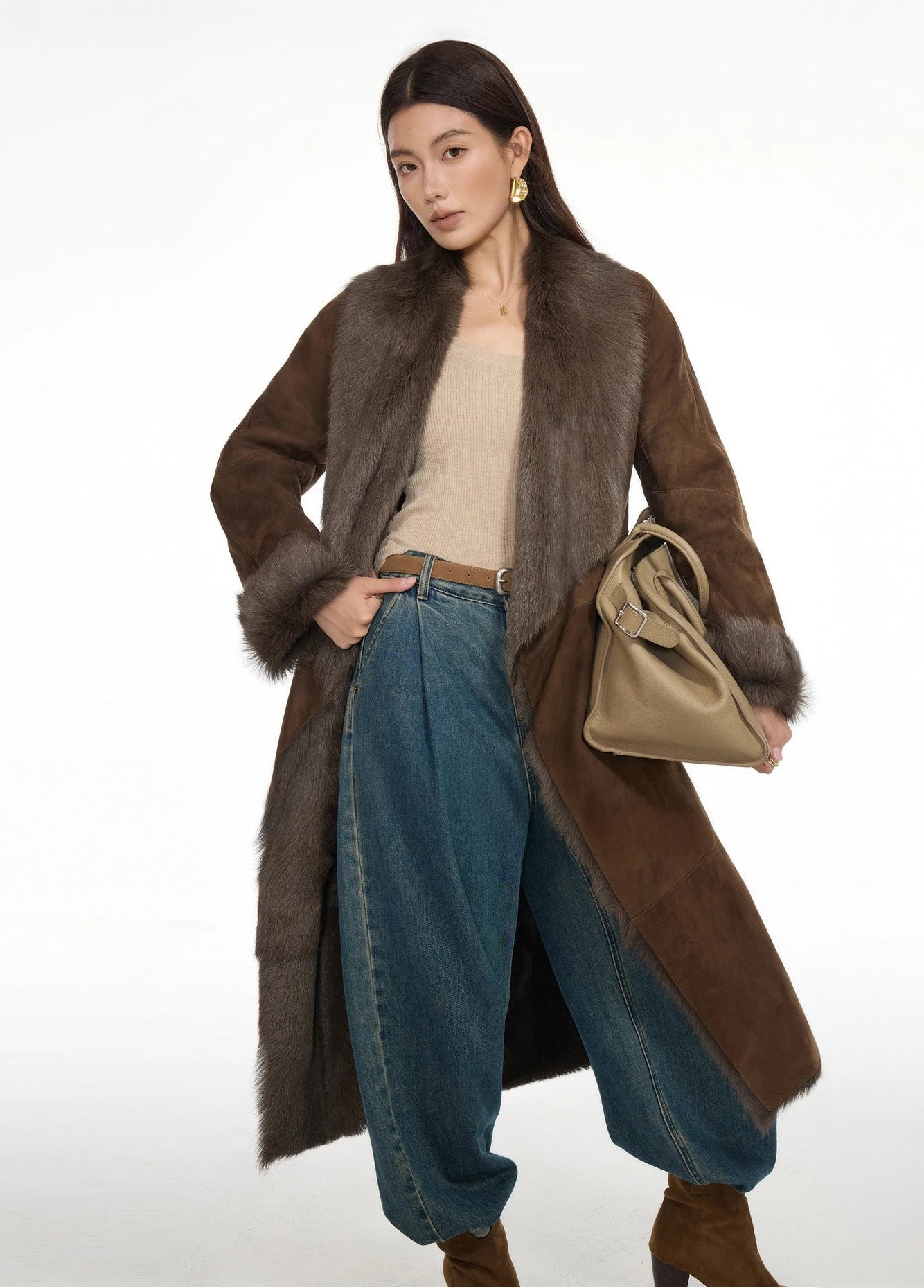 Model posing with one hand on hip and the other holding a bag, dressed in the wide-lapel Woodsy Brown coat — From Borcelleclothes.