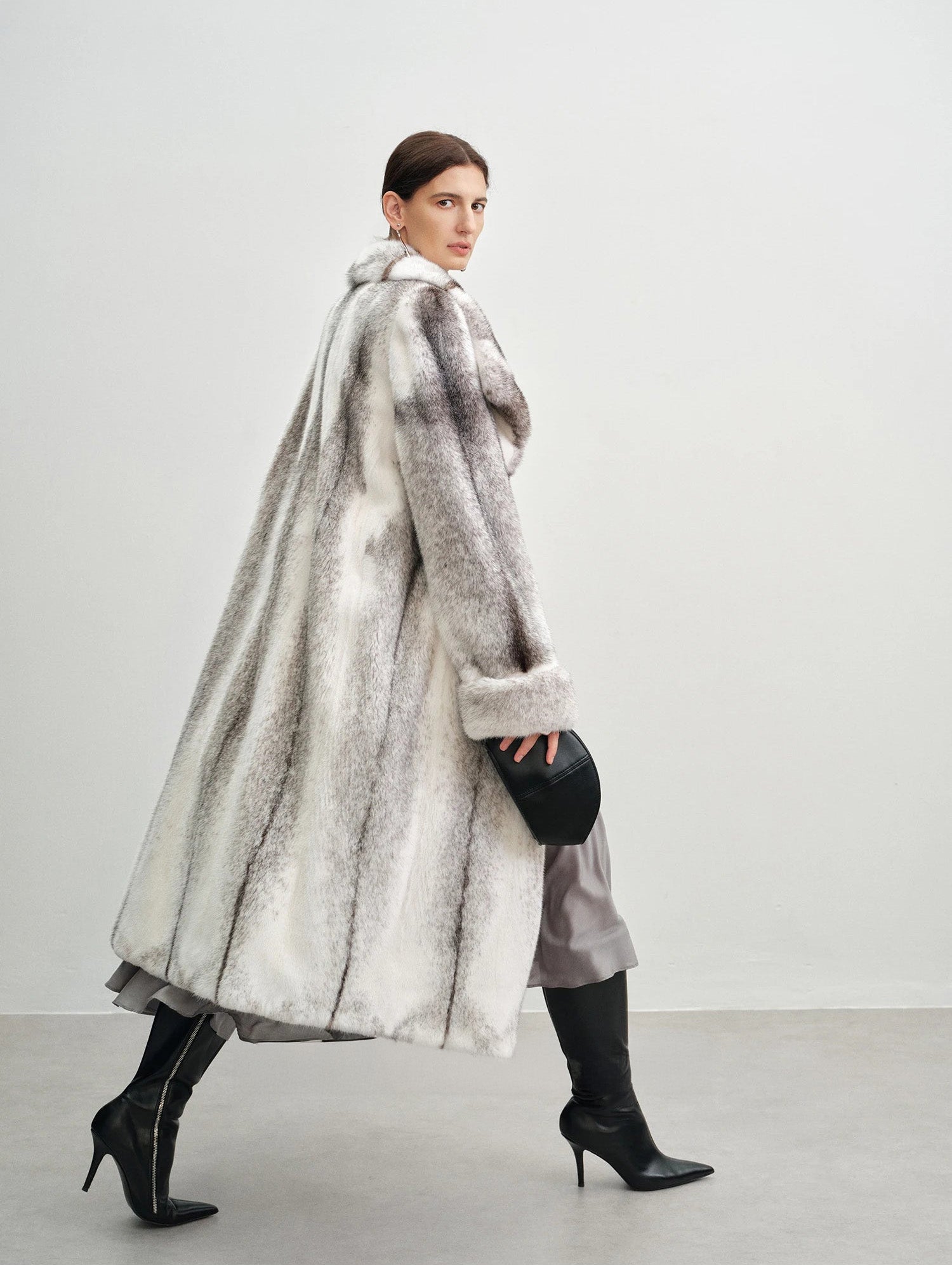 Model walking in profile wearing the cross mink coat — From Borcelleclothes.