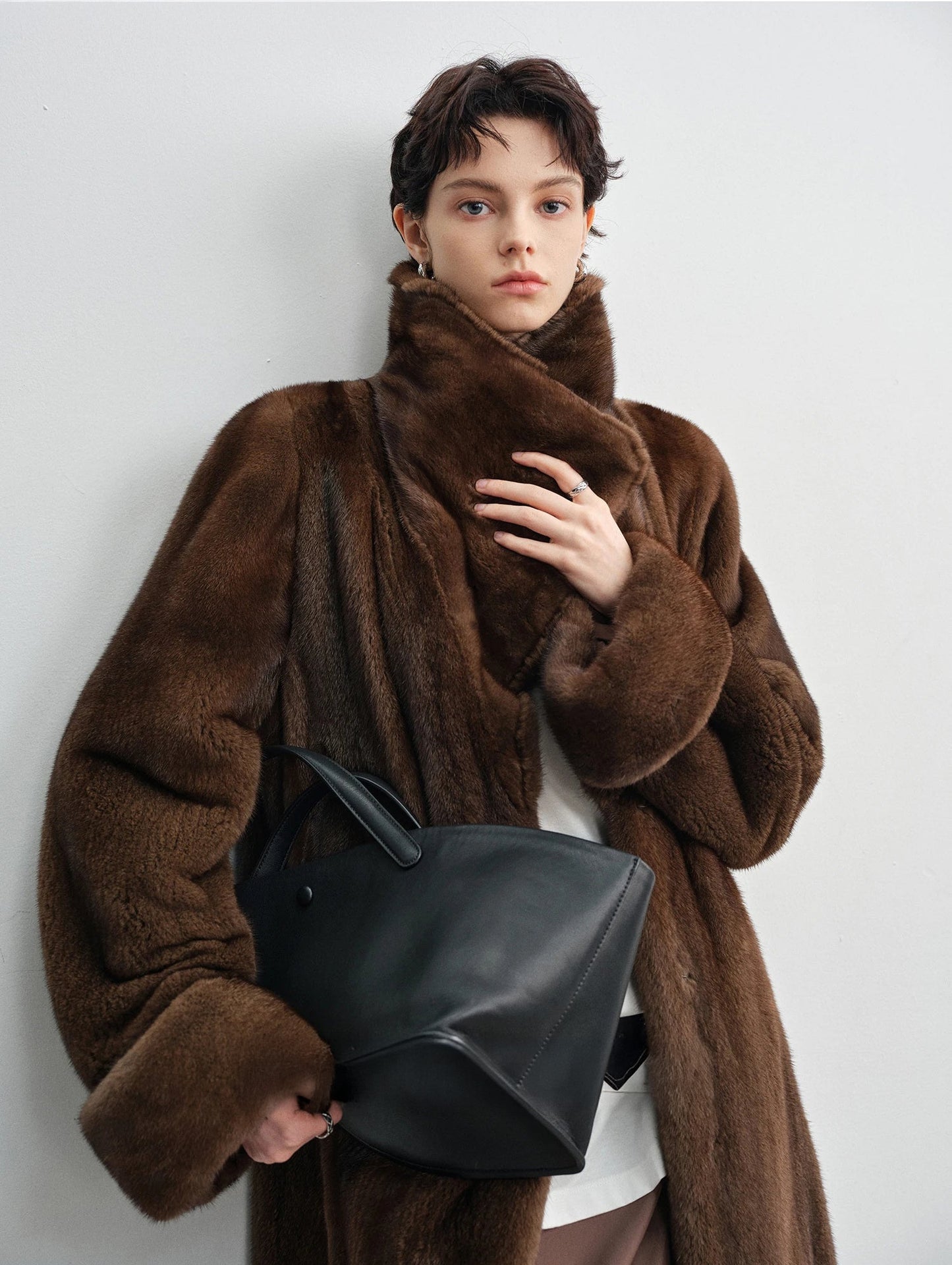 Model holding the lapel and a bag while wearing the brown mink coat — From Borcelleclothes.