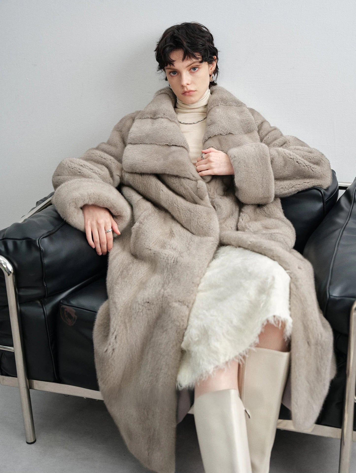 Model seated on a couch in the wide lapel silver blue mink coat — From Borcelleclothes.