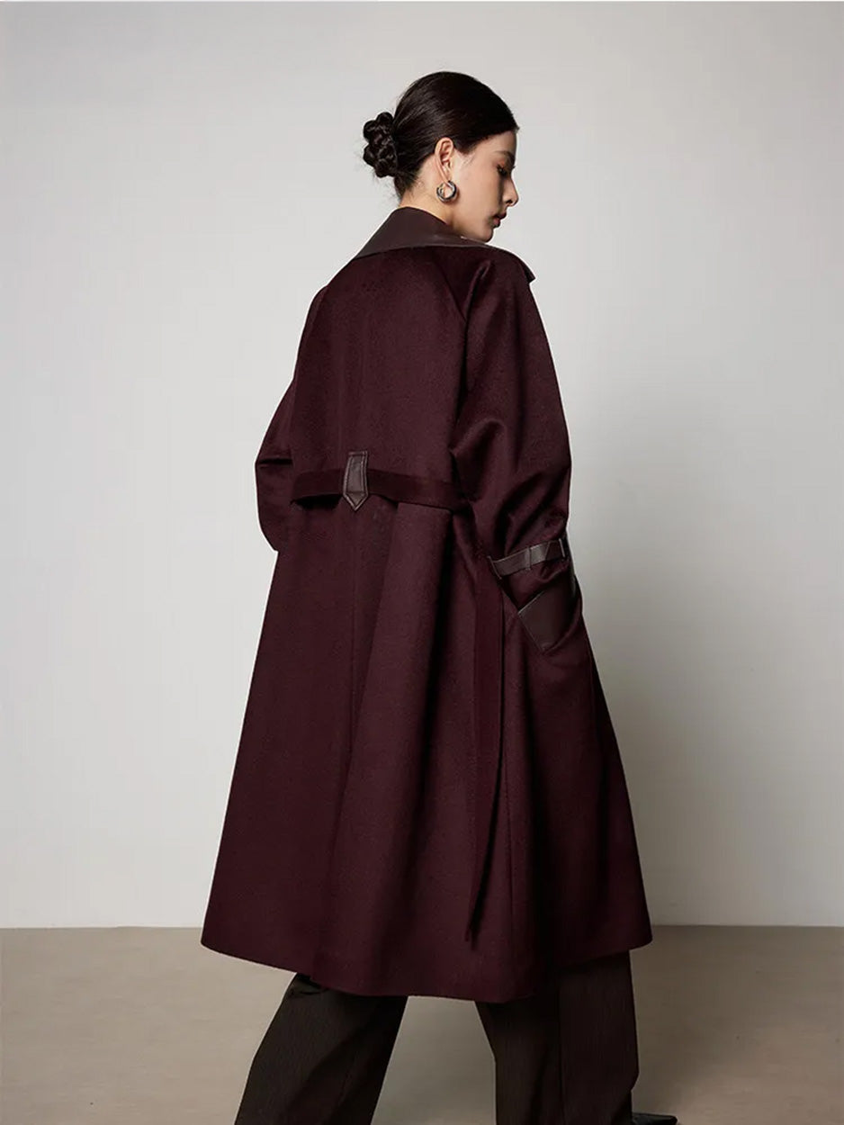 Rear view of the unfastened wool coat on a model, highlighting the raglan sleeves and the decorative leather loop at the back. From Borcelleclothes.