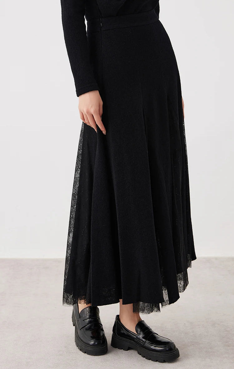 Model turned slightly to the side showcasing a women's wool godet skirt with sheer panels in Game in Black — From Borcelleclothes.
