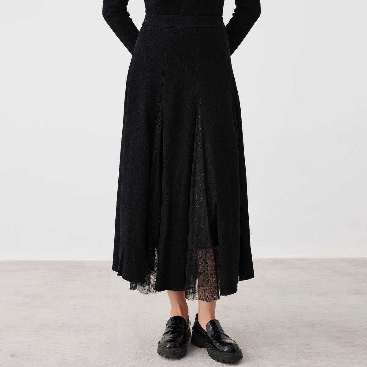 Women's mid-calf merino wool blend godet skirt in Game in Black. Structural wool panels open into fluid, sheer mesh inserts overlaid with lace. — From Borcelleclothes.