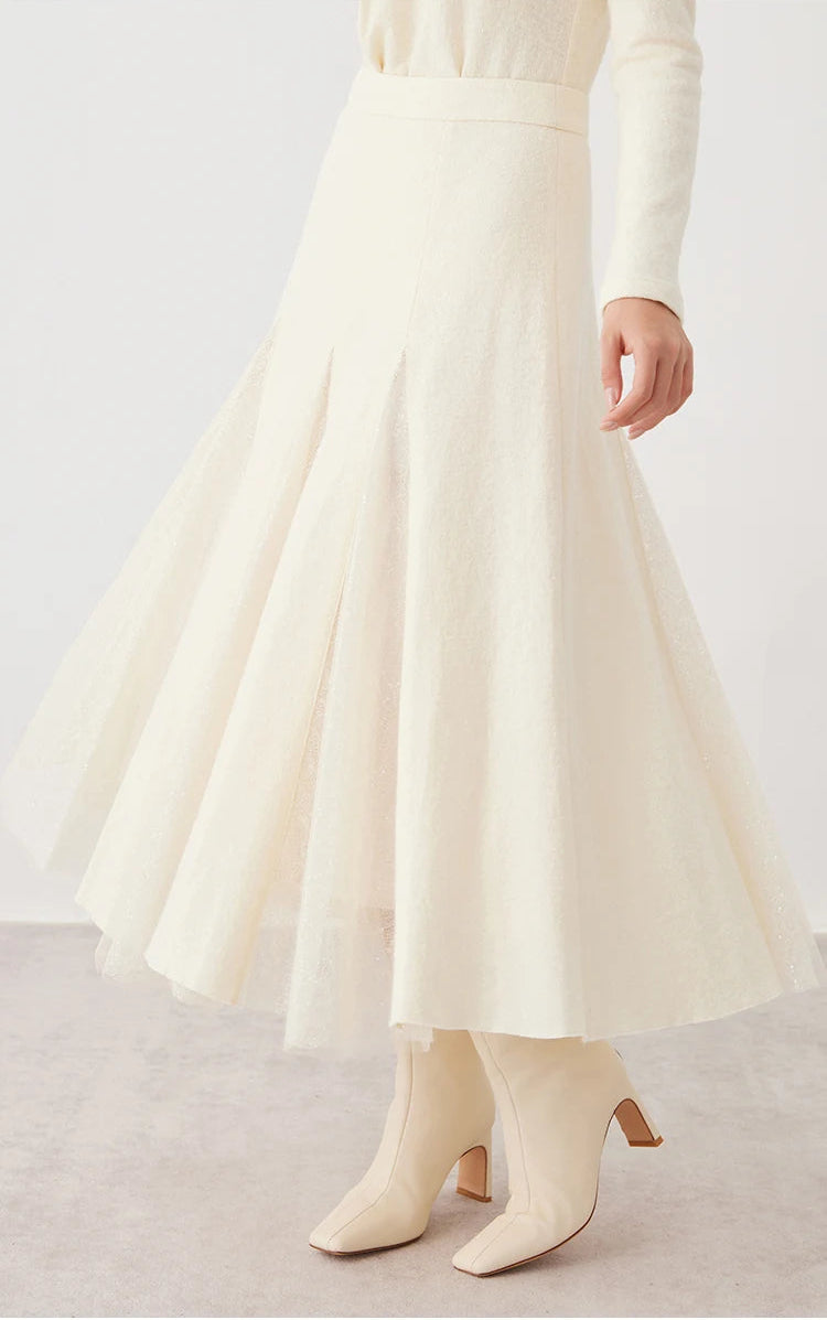 Model swirling to reveal the fluid movement of a women's wool godet skirt with sheer panels in Godet Summer — From Borcelleclothes.