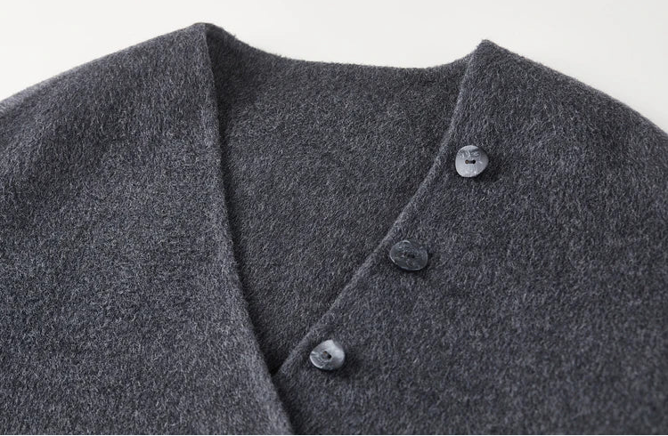 Close-up of the deep V-neckline and the sculptural row of buttons on the grey wool jacket — From Borcelleclothes.