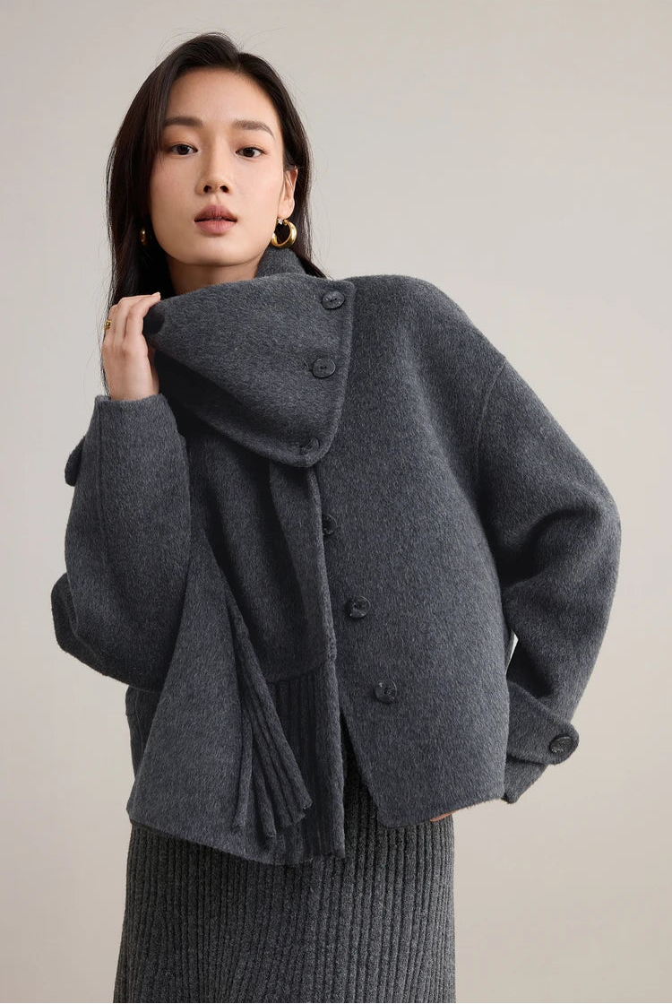 A woman gracefully touching the scarf of her grey double-sided wool jacket — From Borcelleclothes.