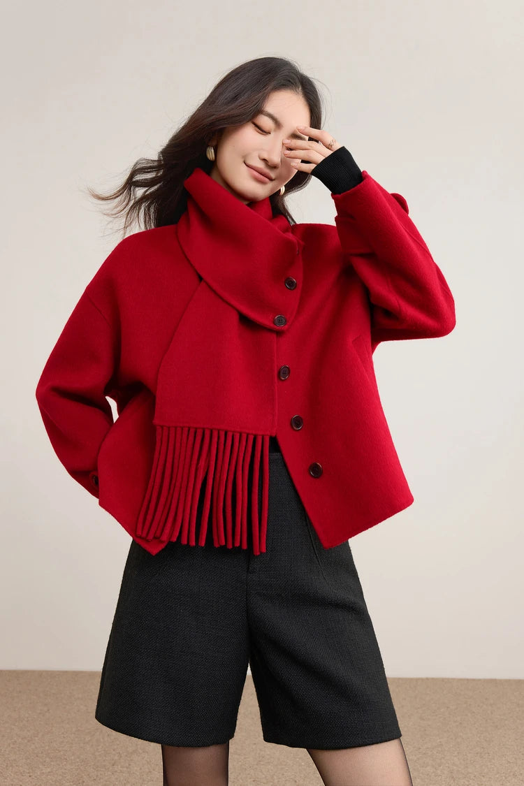 A playful, intimate moment of a woman in a red jacket lightly touching her face with the scarf — From Borcelleclothes.