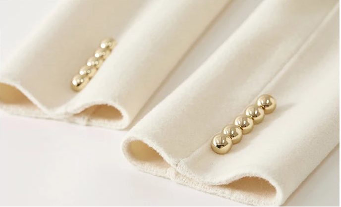 Close-up of the jacket cuff adorned with five matching golden buttons in a rhythmic row — From Borcelleclothes.