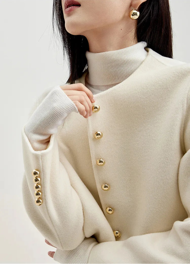 Model’s arm bent to highlight the rhythmic row of golden sphere buttons on the cuff — From Borcelleclothes.