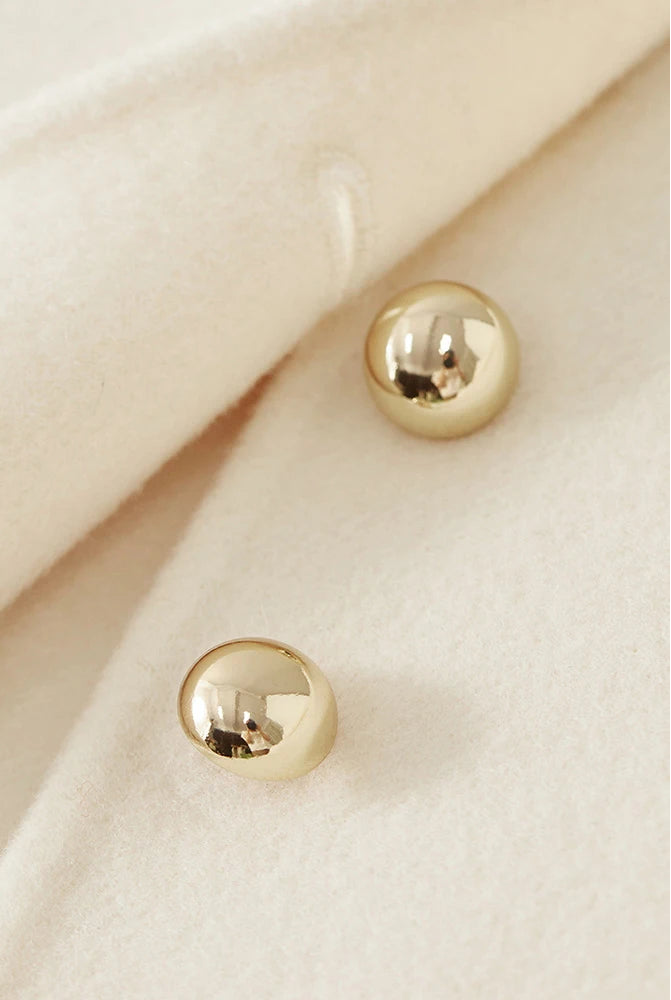 Focused shot of the central golden spheres, catching the light against the cream fabric — From Borcelleclothes.