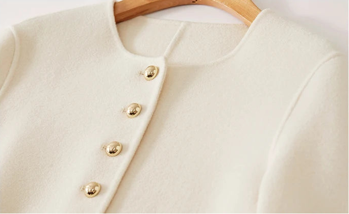 Detailed view of the jacket’s upper part, showcasing the round neckline and the first golden buttons — From Borcelleclothes.