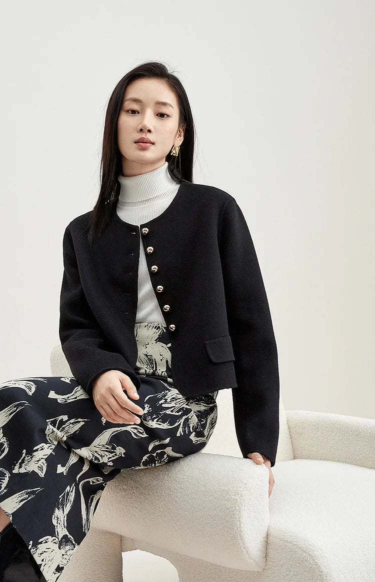 Woman in a Midnight Sax jacket sitting in an armchair, reflecting a moment of quiet serenity and grace — From Borcelleclothes.