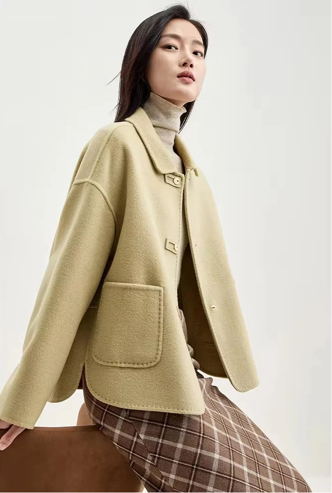 Model perched on the back of an armchair in a women's wool jacket with graphic loop detail — From Borcelleclothes.