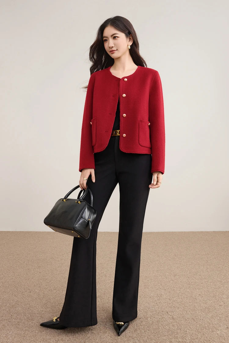 A woman in a vibrant Betta Crimson wool jacket holding a black bag, showcasing the bold color and gold-tone button details. — From Borcelleclothes.