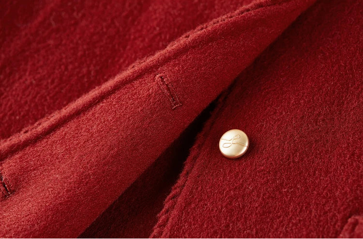 Detailed view of a gold-tone embossed button on the Betta Crimson wool jacket, reflecting the artisanal craftsmanship. — From Borcelleclothes.