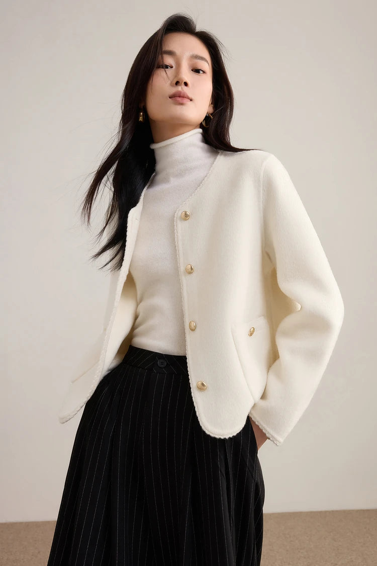 A woman in the Tumbled Shell wool jacket with her hands in her pockets, demonstrating the warm, matte finish of the light cream wool. — From Borcelleclothes.