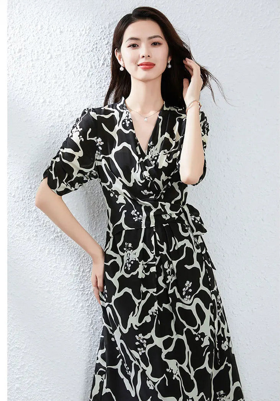 A moment of introspection: a woman adjusting her hair while wearing the Rorschach silk dress, highlighting the grace of the neckline and the subtle texture of the silk. — From Borcelleclothes.