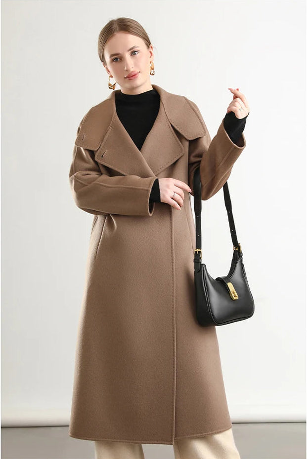 Elegance in the everyday; a woman carrying a bag on her elbow, the Allspice coat from Borcelleclothes providing a warm, spicy aura.