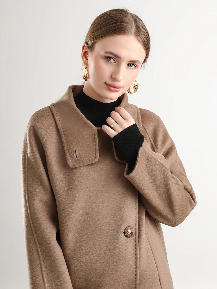 A woman’s hand adjusting the wrap stand collar of her Allspice coat from Borcelleclothes, emphasizing the meticulous hand-finished edges.