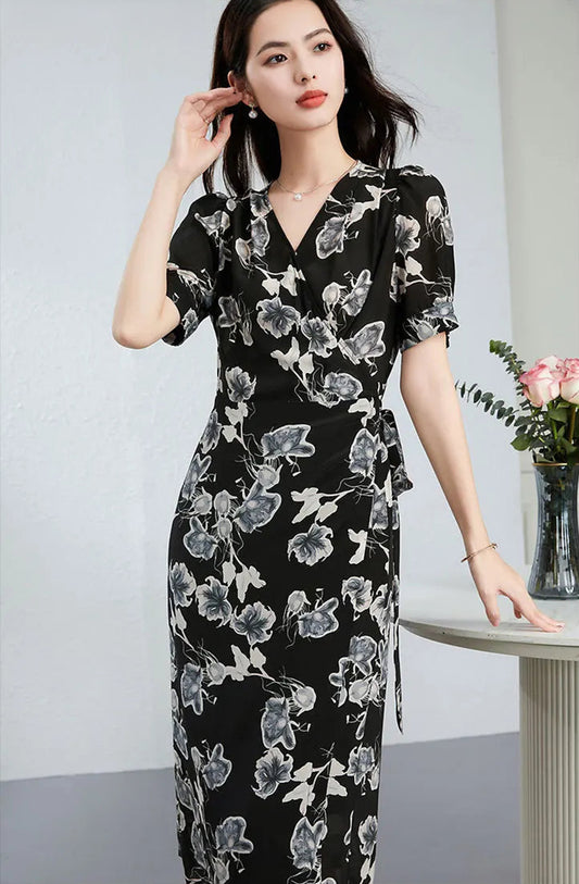A woman in a silk wrap dress gently adjusting her hair, showcasing the elegant movement of the "Drifting Blossom" Guohua print — From Borcelleclothes.