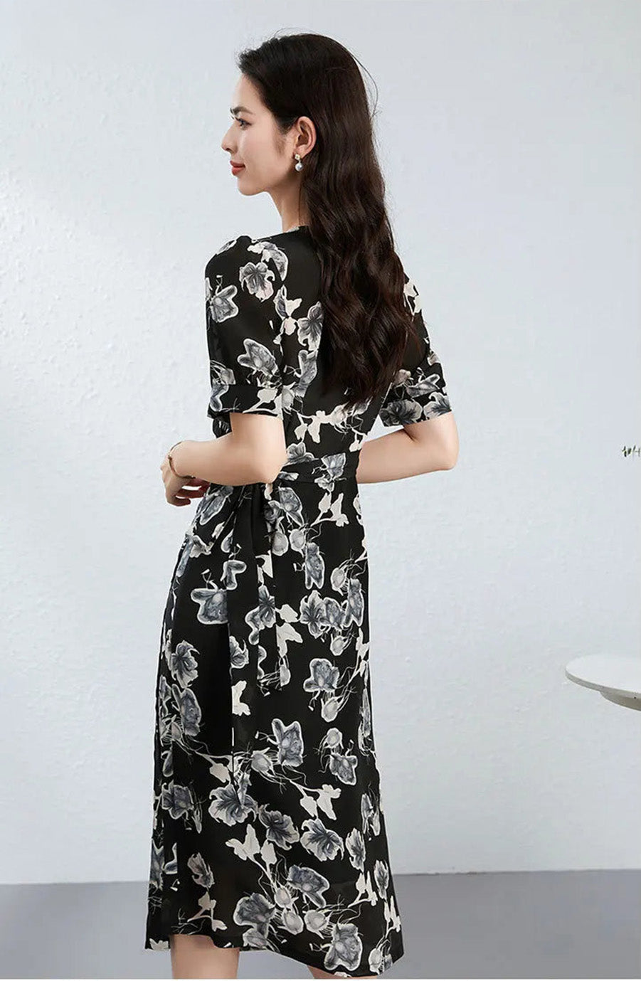 Back view of a woman wearing the wrap dress, showing the seamless flow of the artistic blossom painting across the shoulders — From Borcelleclothes.
