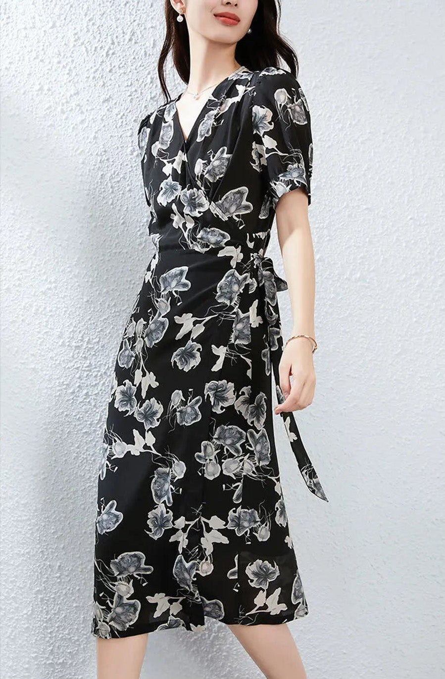 A view of a woman walking from the side, demonstrating the fluid drape of the midi-length silk wrap silhouette — From Borcelleclothes.