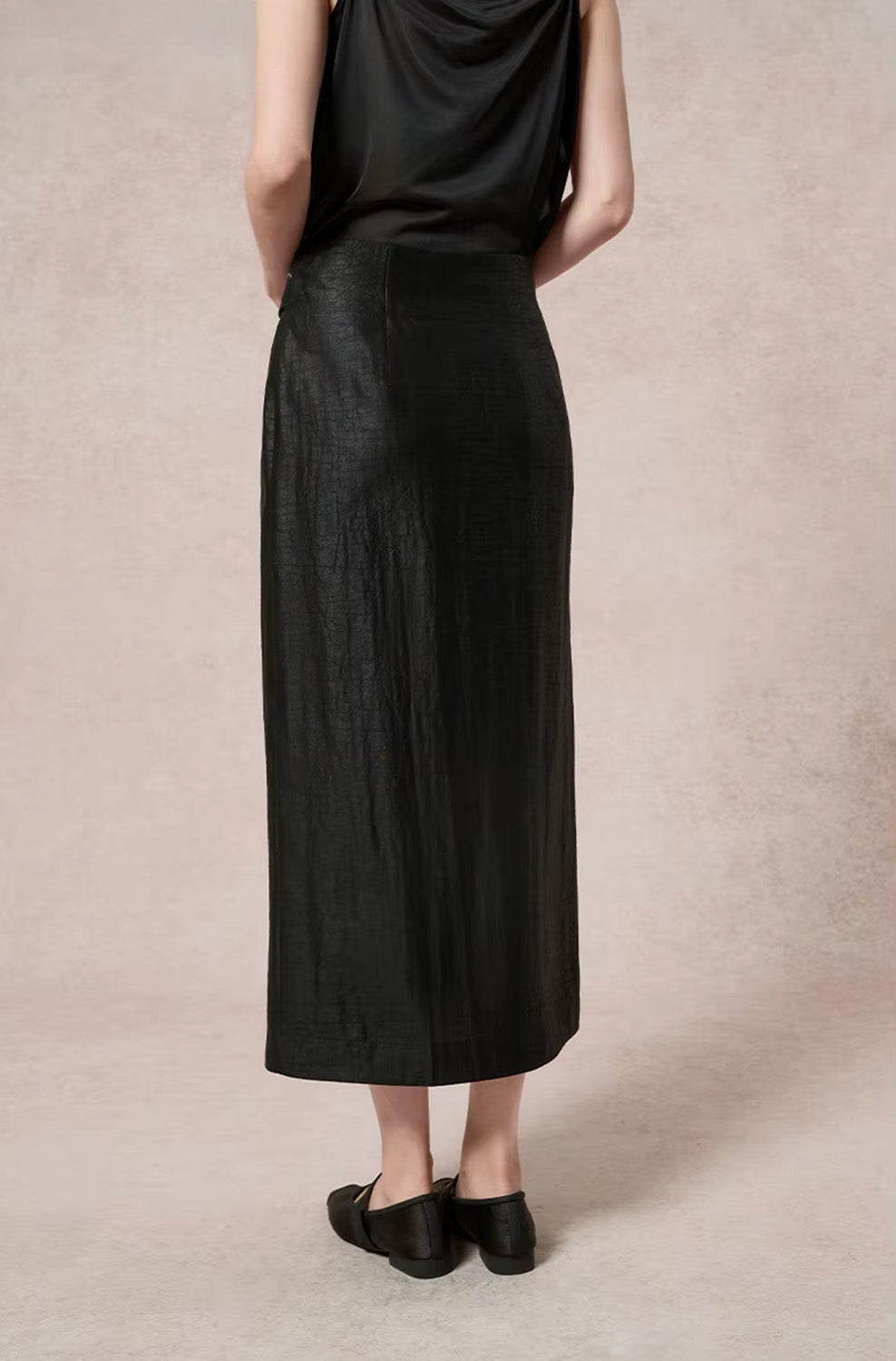 Back view of a model wearing the tailored black structured Xiangyunsha silk midi skirt — From Borcelleclothes.
