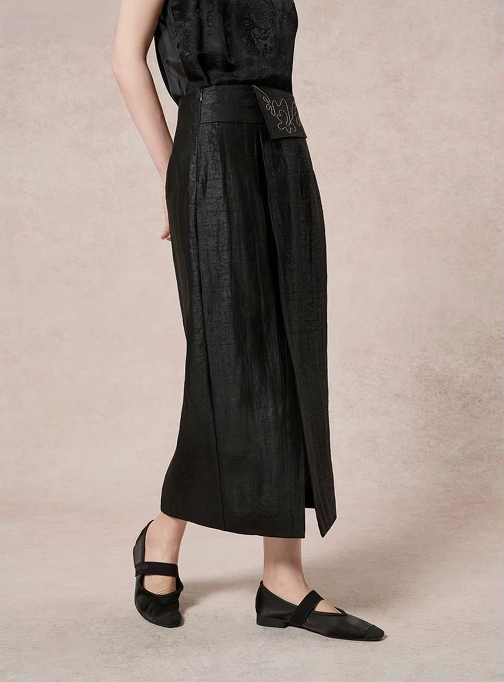 Three-quarter view of a model stepping forward in the black Xiangyunsha silk skirt, highlighting the fluid movement of the free-hanging decorative placket — From Borcelleclothes.