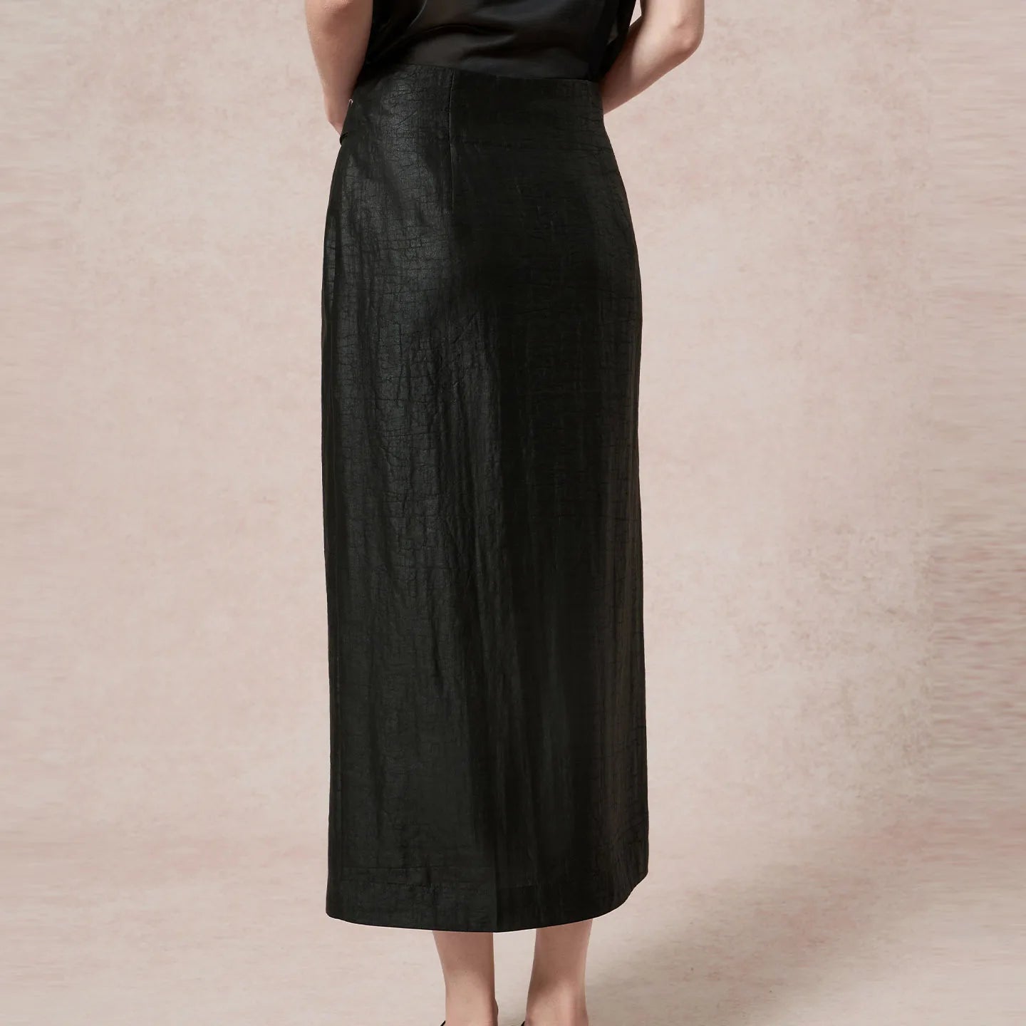 Rear view of the structured black column midi skirt on a standing model — From Borcelleclothes.