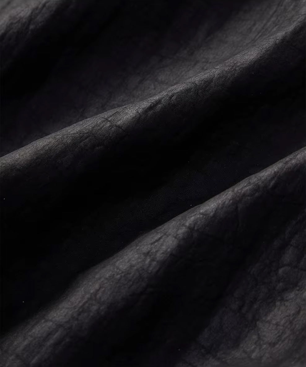 Detailed macro shot of the unique matte-graphite craquelure pattern and mineralized texture on the Xiangyunsha silk — From Borcelleclothes.