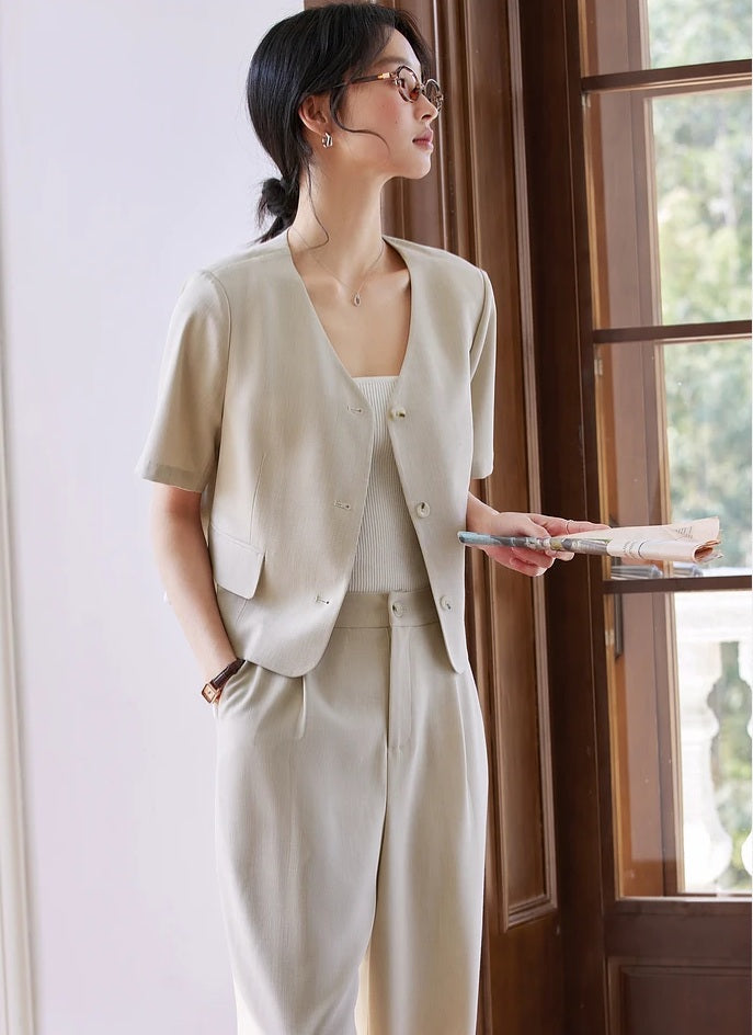 Woman wearing the alabaster two-piece set, standing near a tall window and looking outside. From Borcelleclothes.