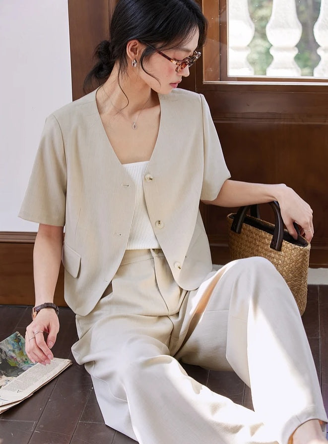 Woman in the alabaster set reaching into a woven bag, highlighting the casual elegance of the outfit. From Borcelleclothes.