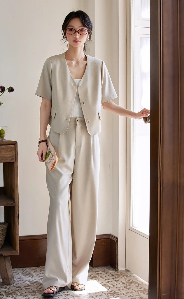 Woman dressed in the alabaster set, lightly touching a door handle in a minimalist interior. From Borcelleclothes.