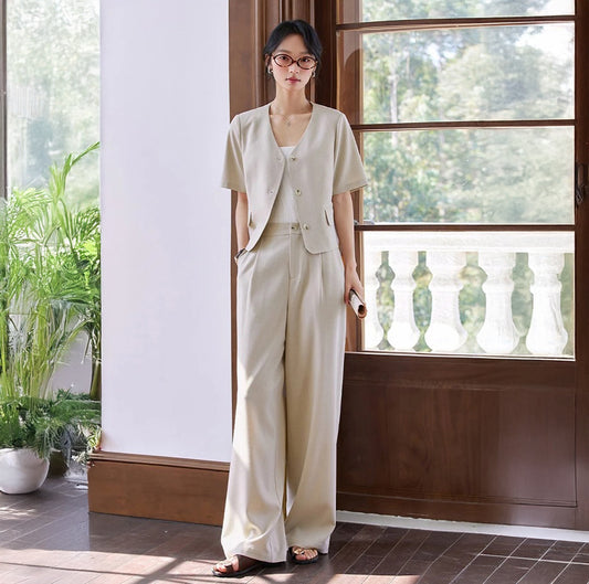 Alabaster two-piece set with a cropped short-sleeve jacket and fluid straight-leg trousers in a soft, light beige shade. Minimalist silhouette with classic tailoring details. From Borcelleclothes.