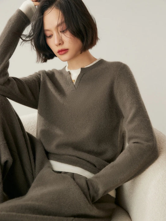 Woman wearing Umber Alashan cashmere sweater with insert detail, sitting on a chair — From Borcelleclothes.