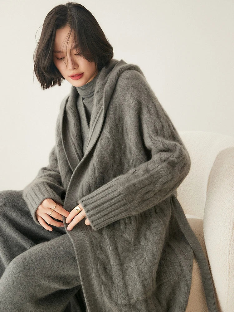 Model seated on a sofa wearing the women's Cable-Knit Cashmere Wool Coat in Flint, highlighting its relaxed, elegant fit and ribbed details, Borcelleclothes.