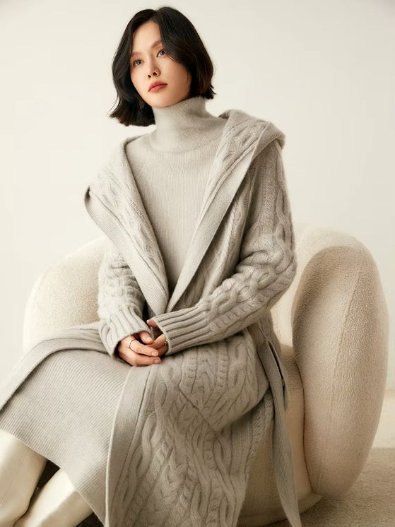 Model seated in an armchair wearing the women's Cable-Knit Cashmere Wool Coat in Pearl Bush, emphasizing its relaxed fit and timeless elegance, Borcelleclothes.