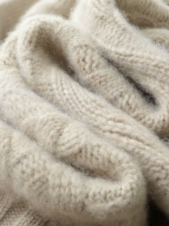 The serpentine folded fabric of the women's Cable-Knit Cashmere Wool Coat in Pearl Bush, emphasizing the soft cashmere texture and elegant draping, Borcelleclothes.