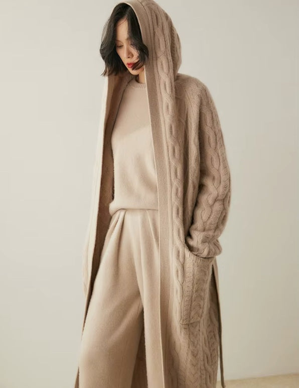Model putting the hood on her head while wearing the women's Cable-Knit Cashmere Wool Coat in Soft Amber, showcasing its practical and stylish design, Borcelleclothes.