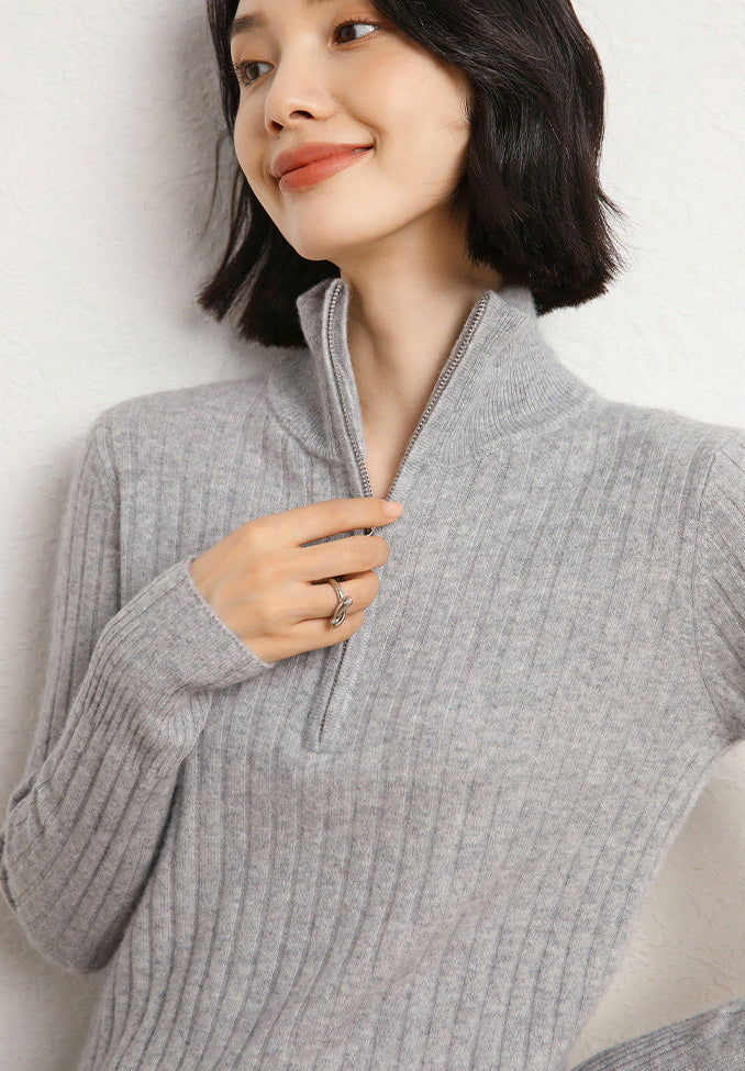 Model touching the zipper wearing a Women’s cashmere half-zip sweater in Tender Grey, featuring shifting rib textures, with stand collar and sculpted finish at hem and cuffs — From Borcelleclothes.